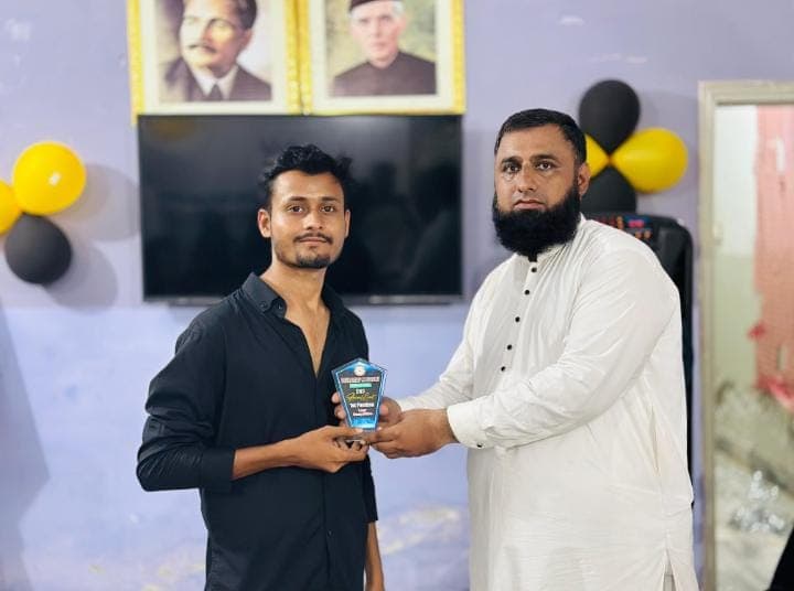 A student receives an award shield from his instructor